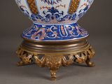 a blue and white vase sitting on a gold stand