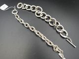 un gros plan sur une paire de bracelets à chaîne en argent posés sur une surface noire