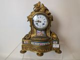 a gold clock sitting on a glass shelf on a white wall