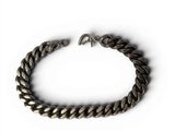 a close up of a metal bracelet on a white surface