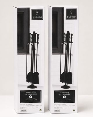 une paire d'accessoires de cheminée en métal noir, présentés dans un coffret posé sur une surface blanche