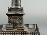 statue of a column on a wooden base with a fence around it