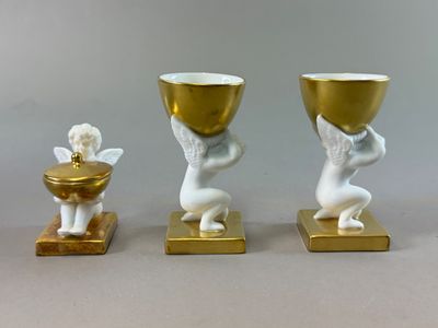 three statues of angels holding cups and a gold bowl