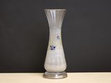 un vase en verre posé sur une table, avec un mur noir en arrière-plan