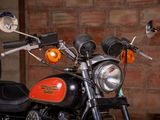 a black and orange motorcycle parked in front of a brick wall
