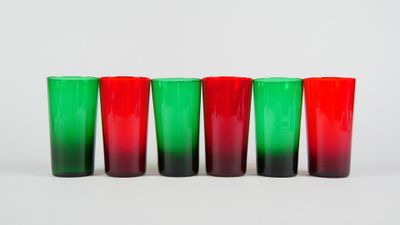 quatre verres à shot rouges et verts alignés sur un fond blanc