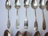 several silver spoons are arranged in a row on a white surface