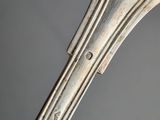 an antique silver plate spoon with a curved handle on a gray background
