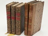 three old books sitting next to each other on a white surface