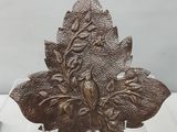 sculpture représentant une feuille, posée sur un socle transparent, sur une surface blanche
