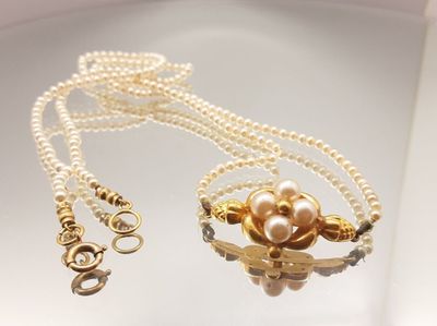 necklace with pearls and a gold clasp on a white surface