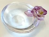 un bol en verre contenant une fleur, posé sur une table