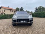 a grey porsche cayen is parked in a gravel parking lot