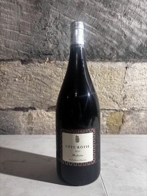 a bottle of wine sitting on a table next to a brick wall