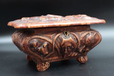 une vieille boîte en bois ornée de sculptures, posée sur une surface noire
