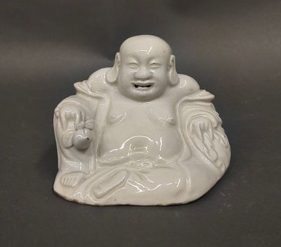 a small statue of a smiling buddha sitting on a table