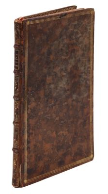 un vieux livre à la couverture brune posé sur une surface blanche