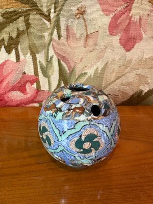 un petit vase posé sur une table, avec un coussin en arrière-plan