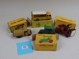 cinq camions miniatures et une boîte posés sur une surface blanche
