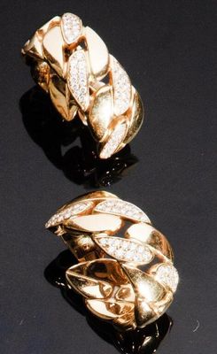 une paire de boucles d'oreilles en or et diamants posées sur un fond noir