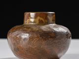 a brown vase that is sitting on a white table