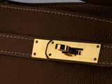 the handle of a brown leather bag with a gold buckle