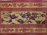 un vieux tapis orné d'oiseaux et de fleurs sur fond rouge