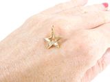 a woman ' s hand holding a gold ring with a star on it