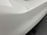 the front bumper of a white car with rust on it