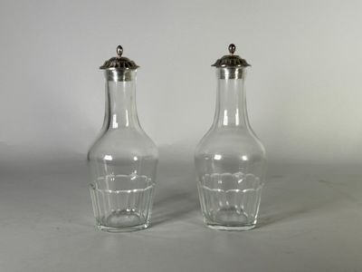une paire de salières et poivrières en verre transparent posées sur un plan de travail blanc