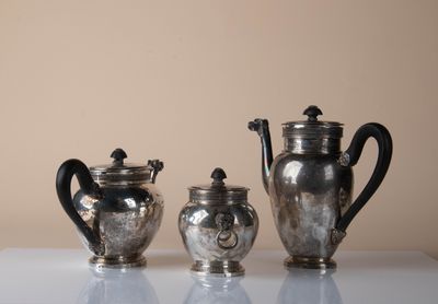 three silver teapots sitting on a white table