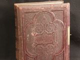 an old book sitting on top of a black cloth covered table