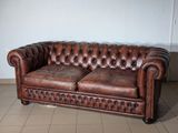 leather chesterfield sofa in a room with tile flooring and white walls