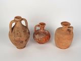 trois vases en argile sont posés les uns à côté des autres sur une surface blanche