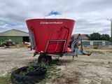 a red tractor trailer parked next to a red farm trailer