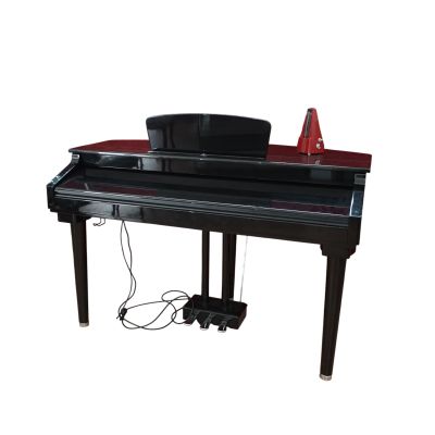 un piano noir posé sur une table, avec un chapeau dessus