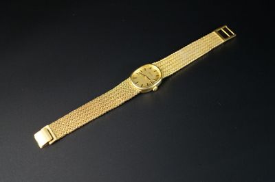 gros plan d'une montre en or sur une surface noire