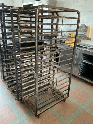 several trays of food sit on a metal rack in a kitchen