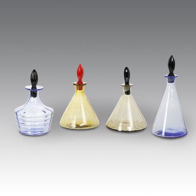 trois flacons de parfum en verre avec des bouchons noirs et un bouchon rouge