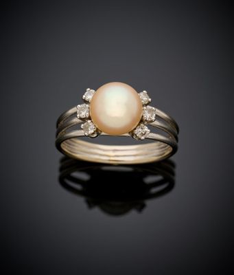 une bague en perles blanches et diamants sur une surface noire