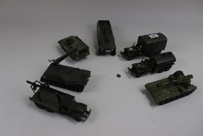 Plusieurs véhicules militaires miniatures sont disposés en cercle sur une surface blanche.