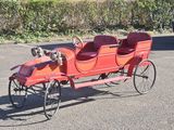 a red horse drawn carriage with a dog sitting in it