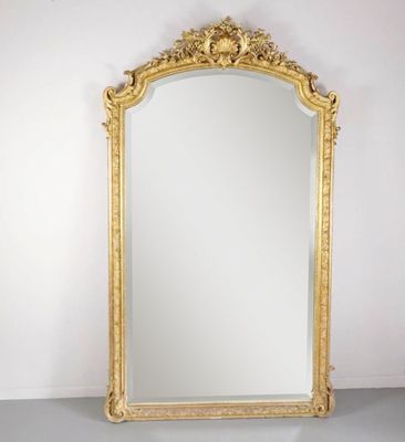 un miroir à cadre doré posé sur une table près d'un mur