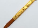 a gold colored pen with a wooden handle on a white surface
