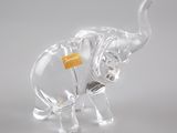 figurine d'éléphant en verre transparent, avec une étiquette jaune accrochée à sa trompe