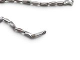 a silver necklace with a long chain on a white surface