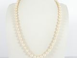 a white pearl necklace on a mannequin with a gold clasp