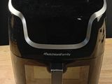 une friteuse à air chaud posée sur une table en bois, à côté d'un couteau