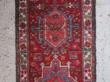 a red rug hanging on a wall next to a white wall