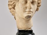 tête de femme en marbre aux cheveux bouclés, posée sur un socle noir